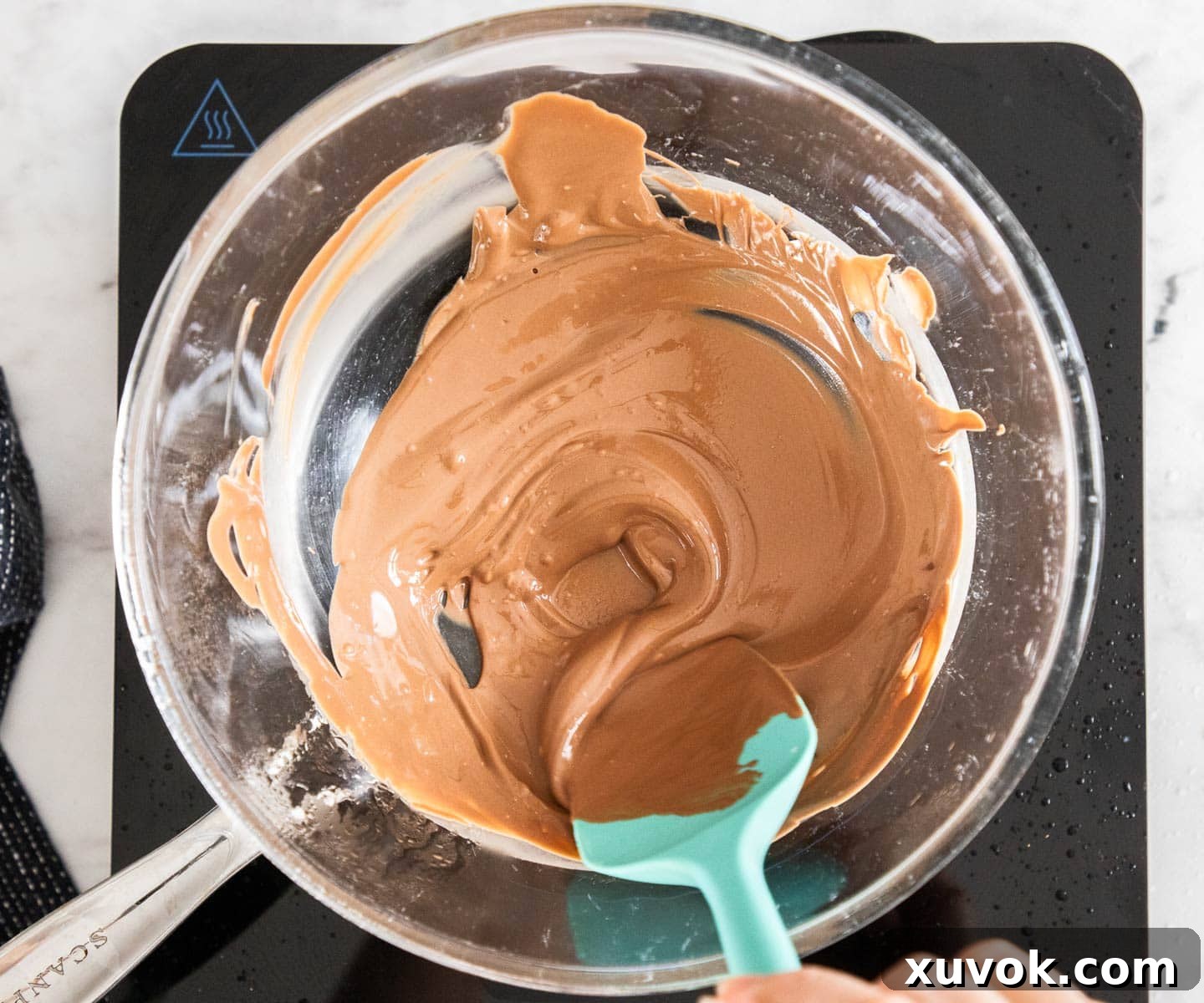 Milk chocolate being melted in a double boiler, essential for the caramel pretzel variation.