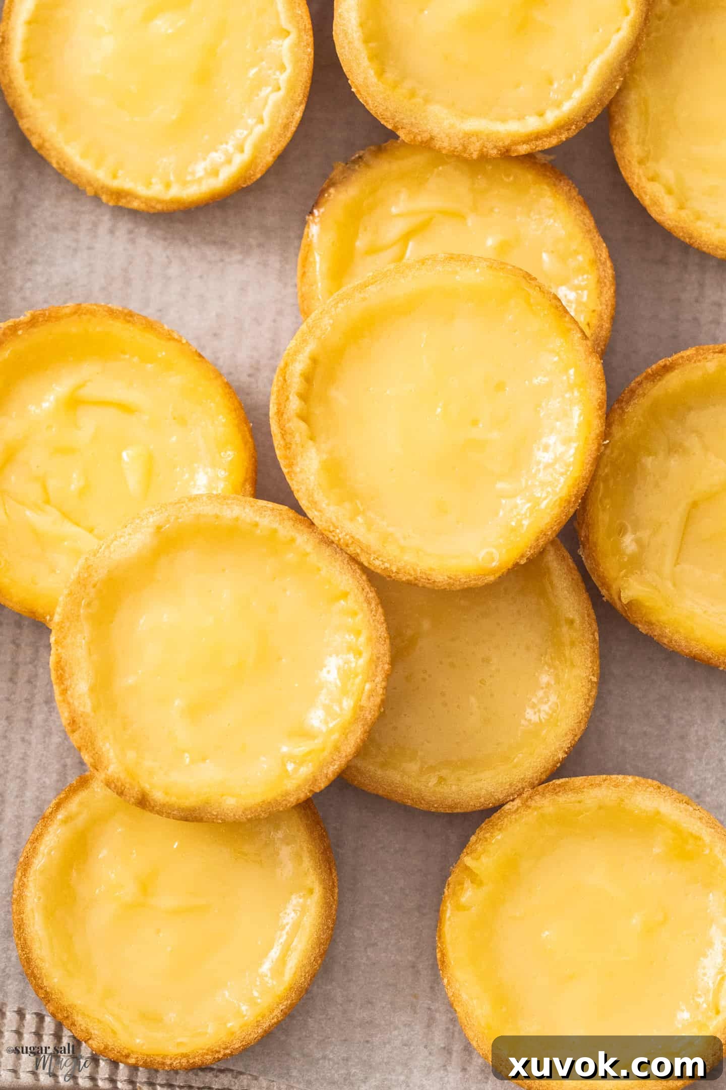 A stunning close-up of beautifully baked lemon tarts arranged on a elegant gold baking tray.