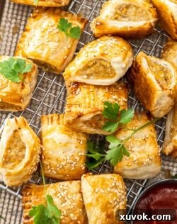 Closeup, top down view of a pile of chicken sausage rolls on a wire rack.