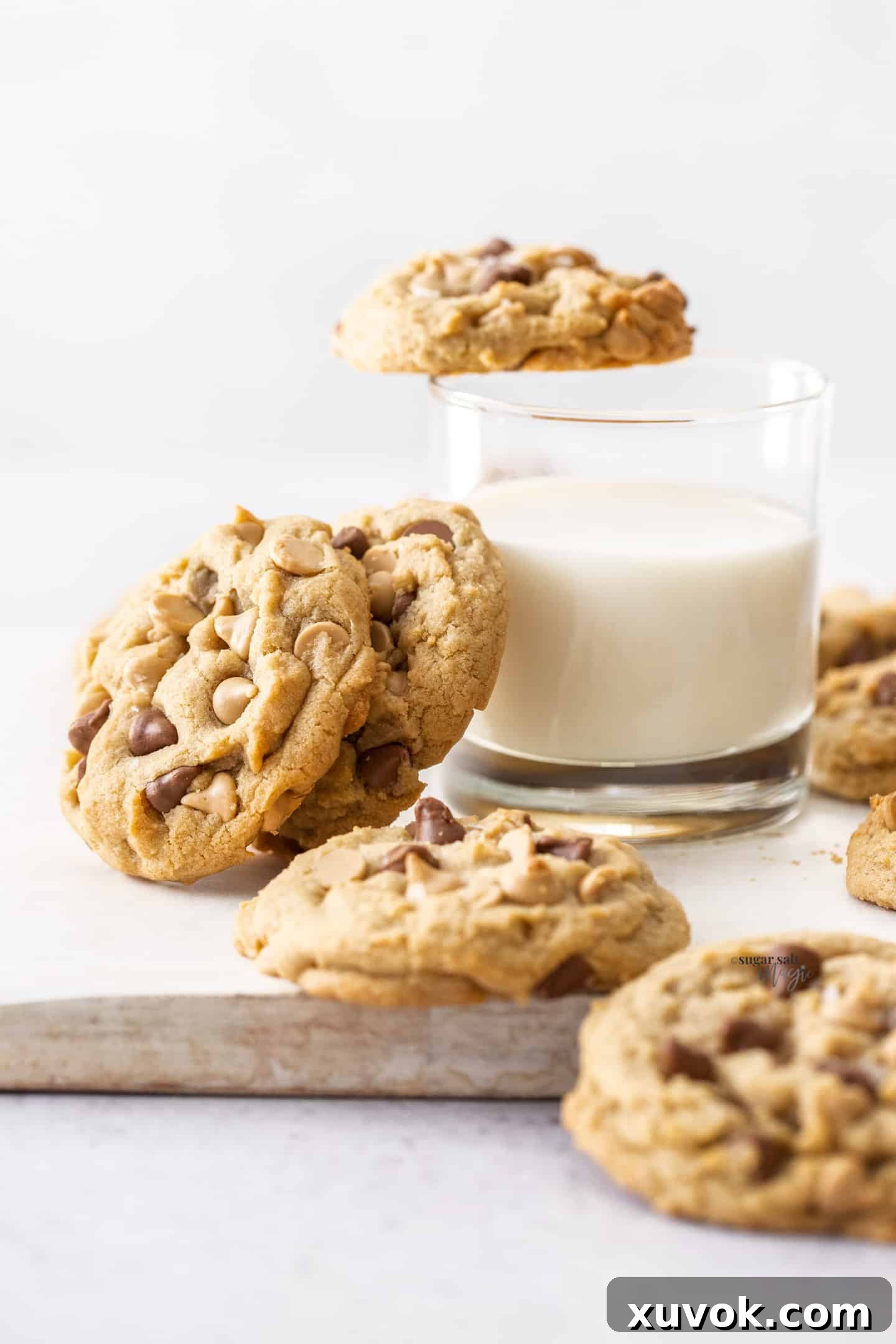 Caramilk cookies leaning up against a glass of milk, showcasing their golden hue and delicious texture.