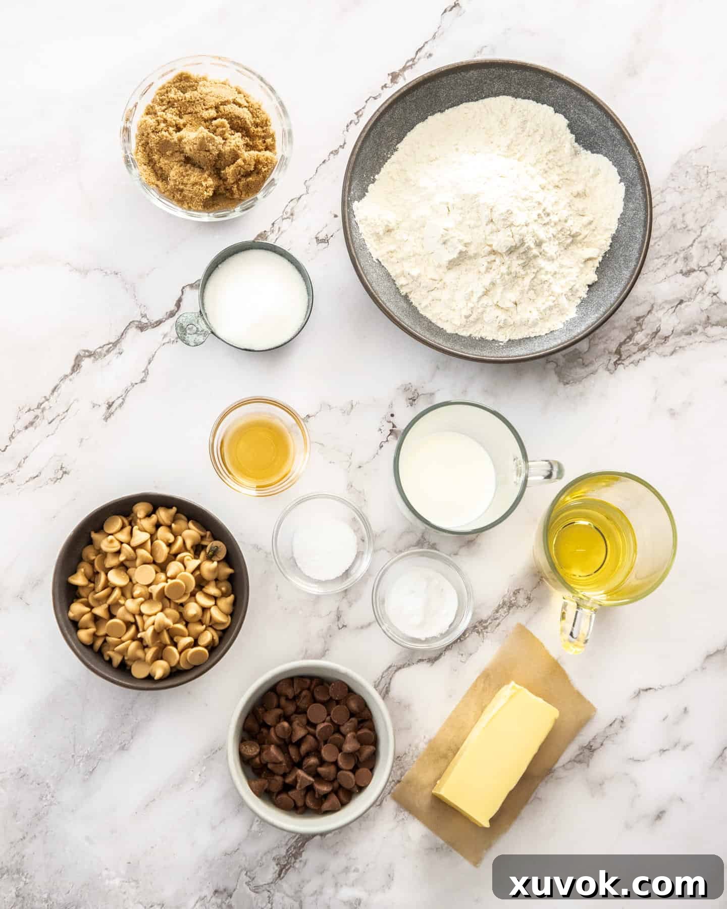 A beautifully arranged selection of ingredients for Caramilk cookies on a pristine marble surface.