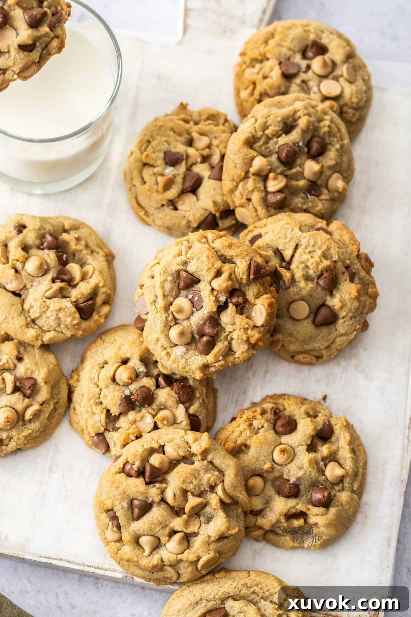 A dozen freshly baked Caramilk cookies arranged on a white wooden board, ready to be enjoyed.