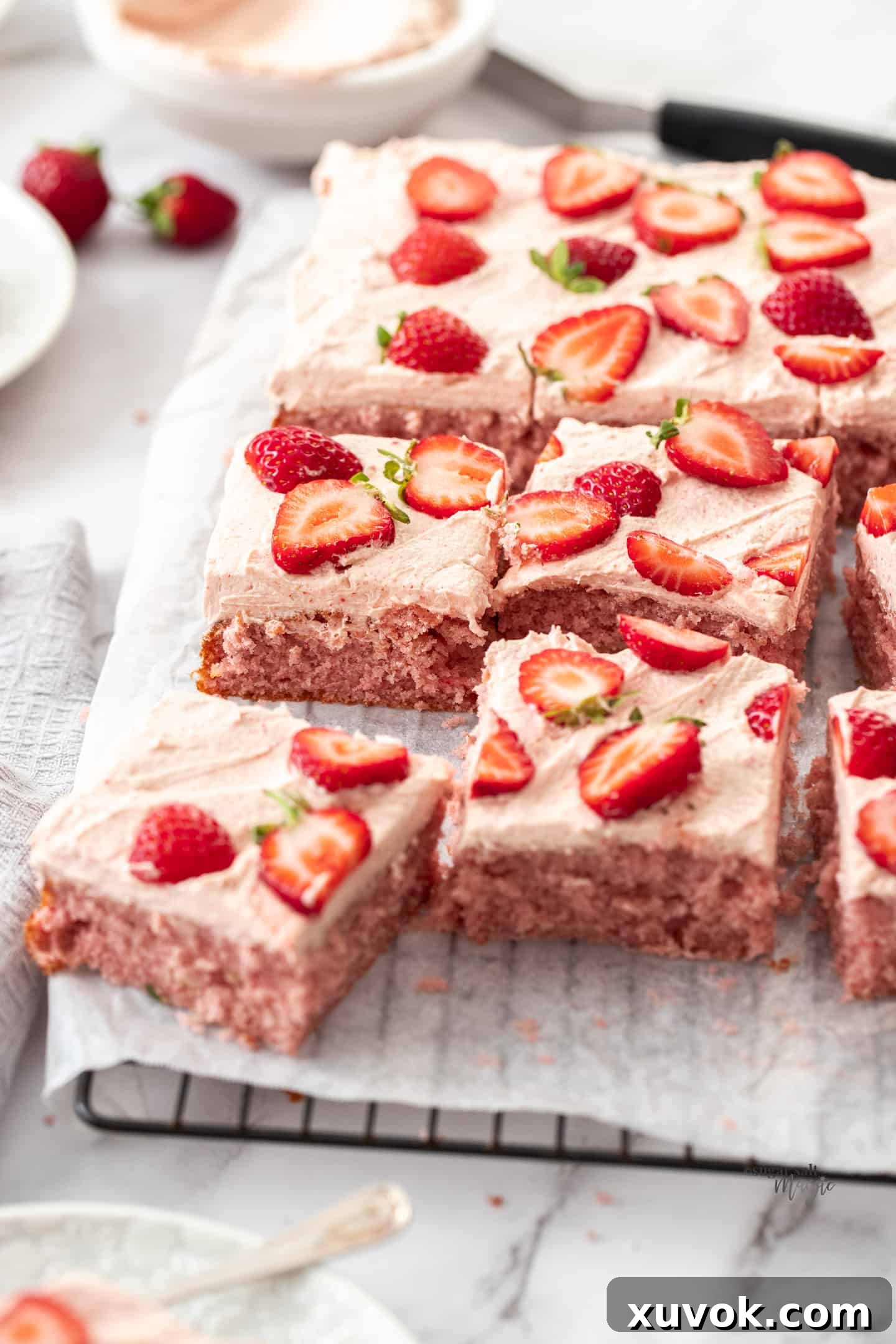 A strawberry sheet cake with some slices cut from it, showcasing its moist texture and creamy frosting.