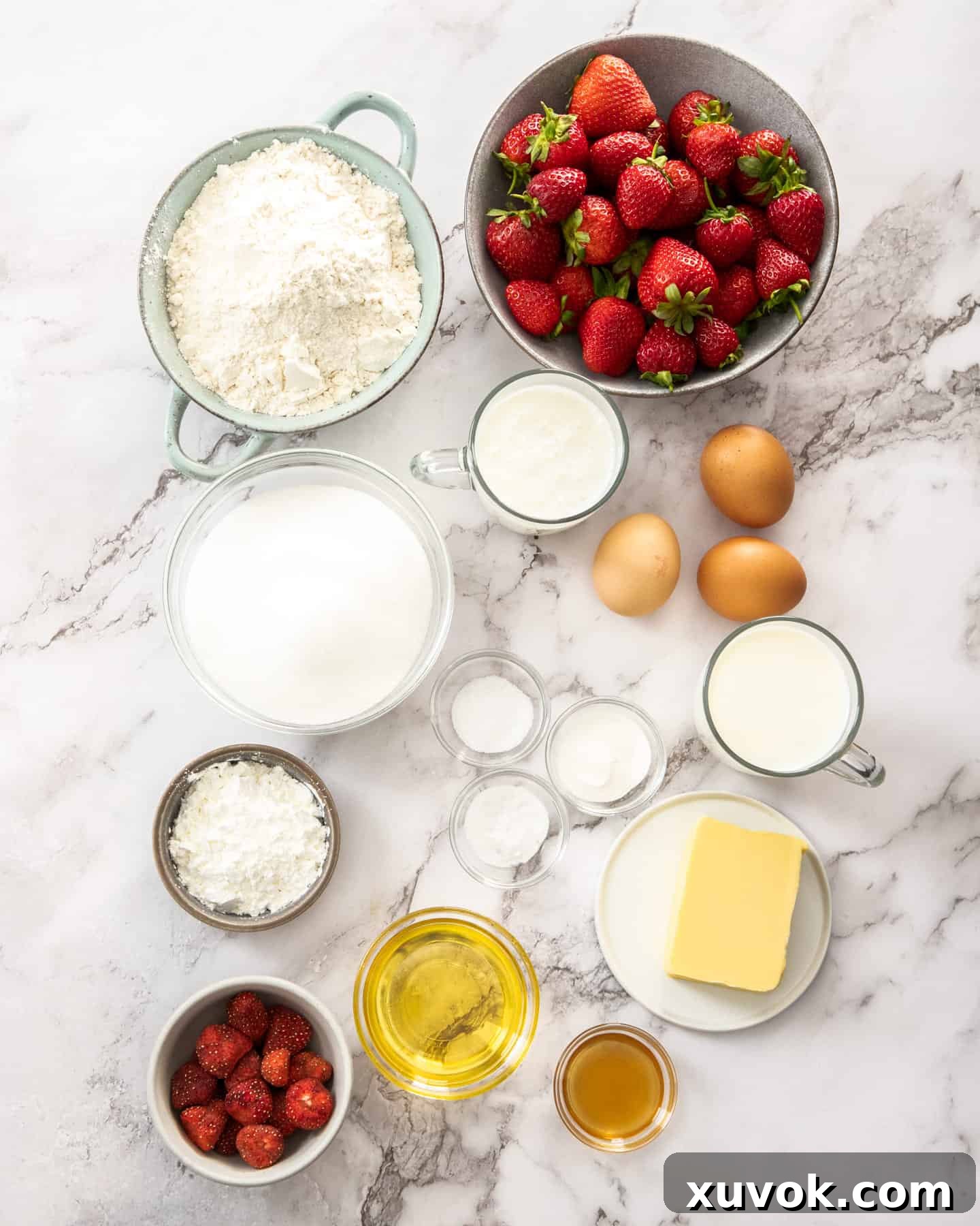 Ingredients for strawberry sheetcake on a marble benchtop, including fresh and freeze-dried strawberries.