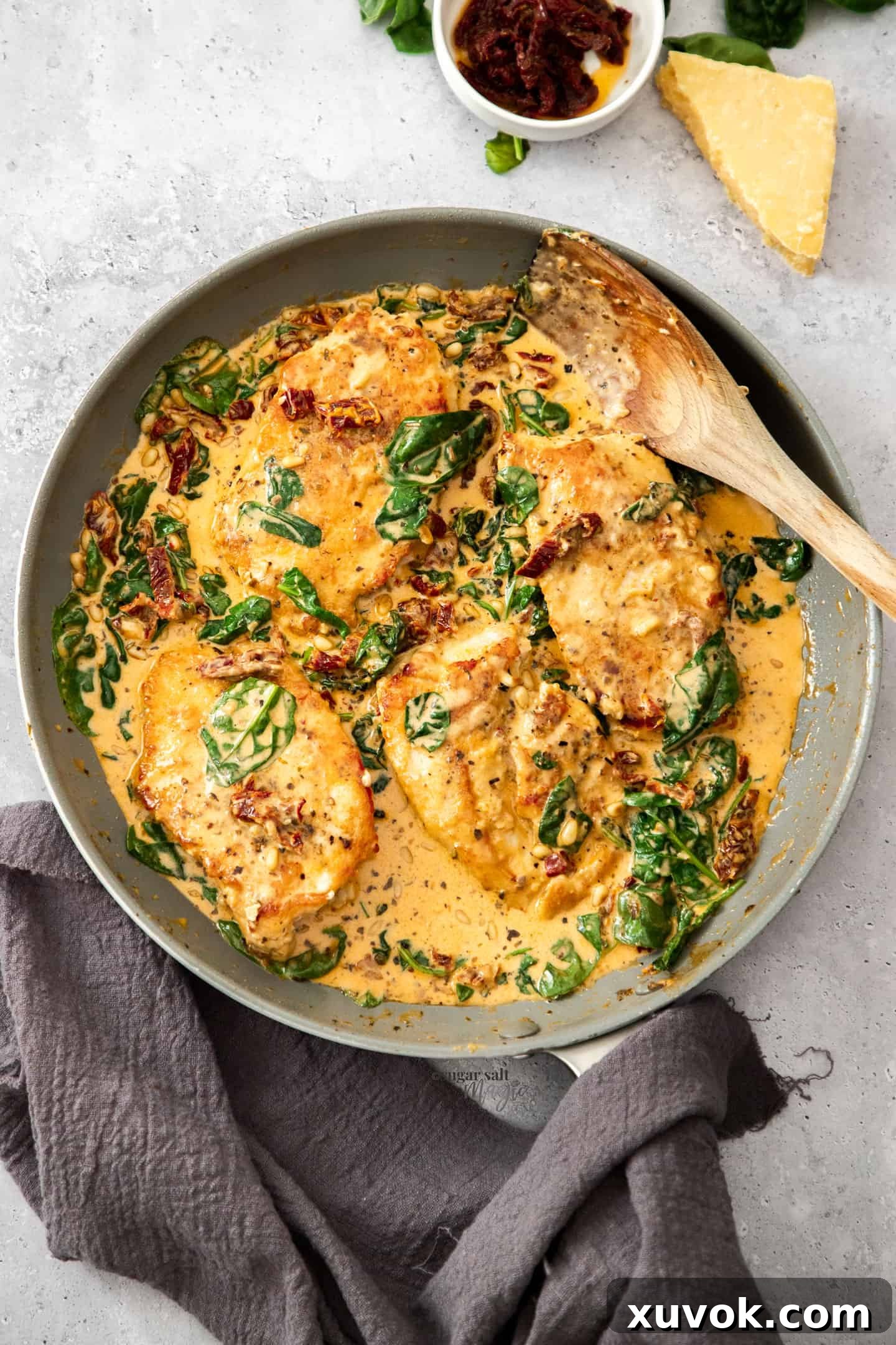 Top down view of a large skillet filled with tuscan chicken ready to be served, garnished with fresh herbs.