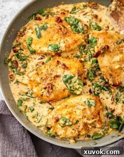 4 pieces of chicken in a creamy sauce in a large skillet, garnished with fresh herbs.
