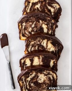 5 slices of marble cake on a tin with a ganache covered knife next to them.