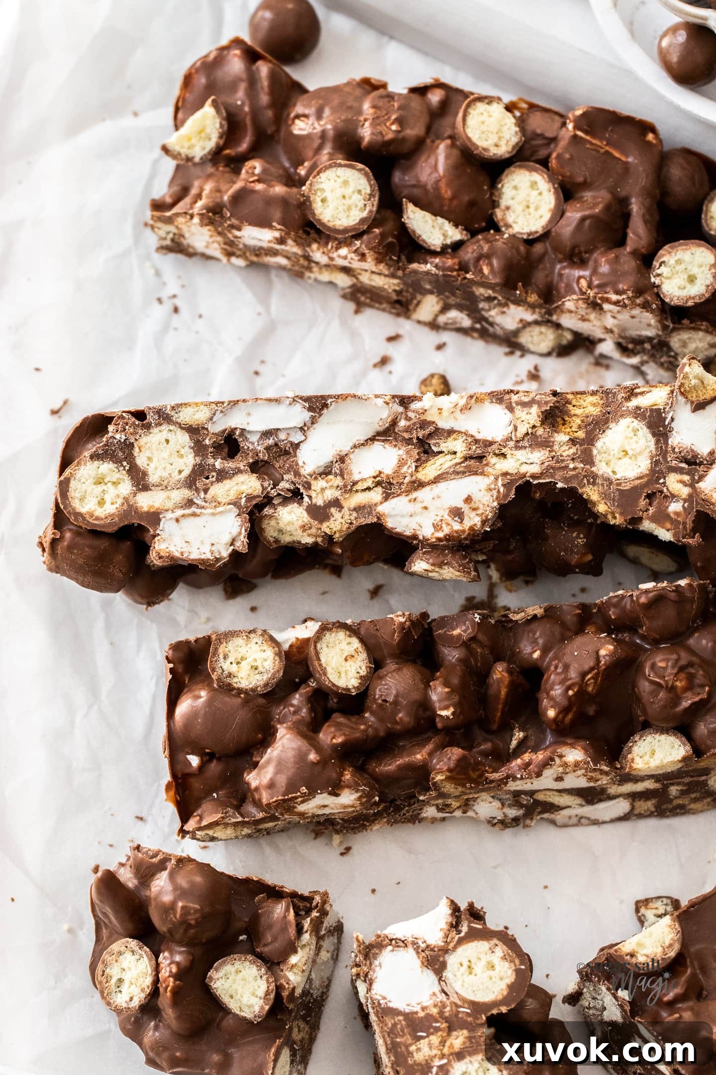 Big slices of Malteser rocky road on a white wooden platter.