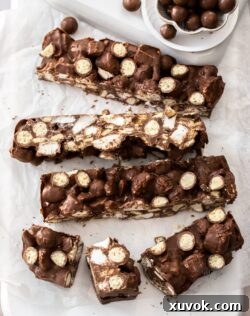Big slices of Malteser rocky road on a white wooden platter.