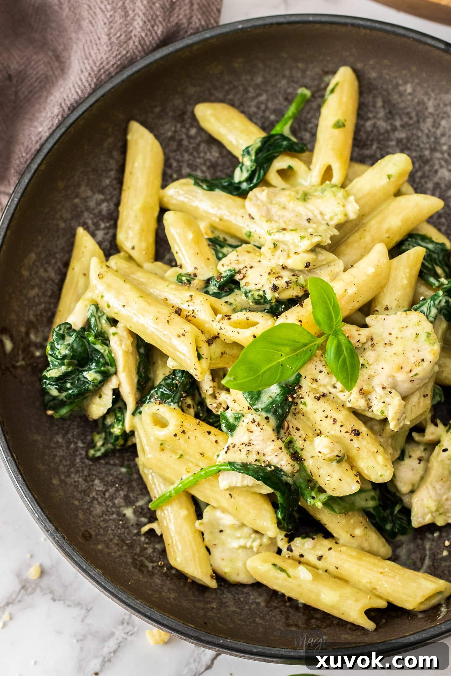 Top down view of creamy chicken spinach pasta in a bowl. A perfect easy weeknight dinner idea.