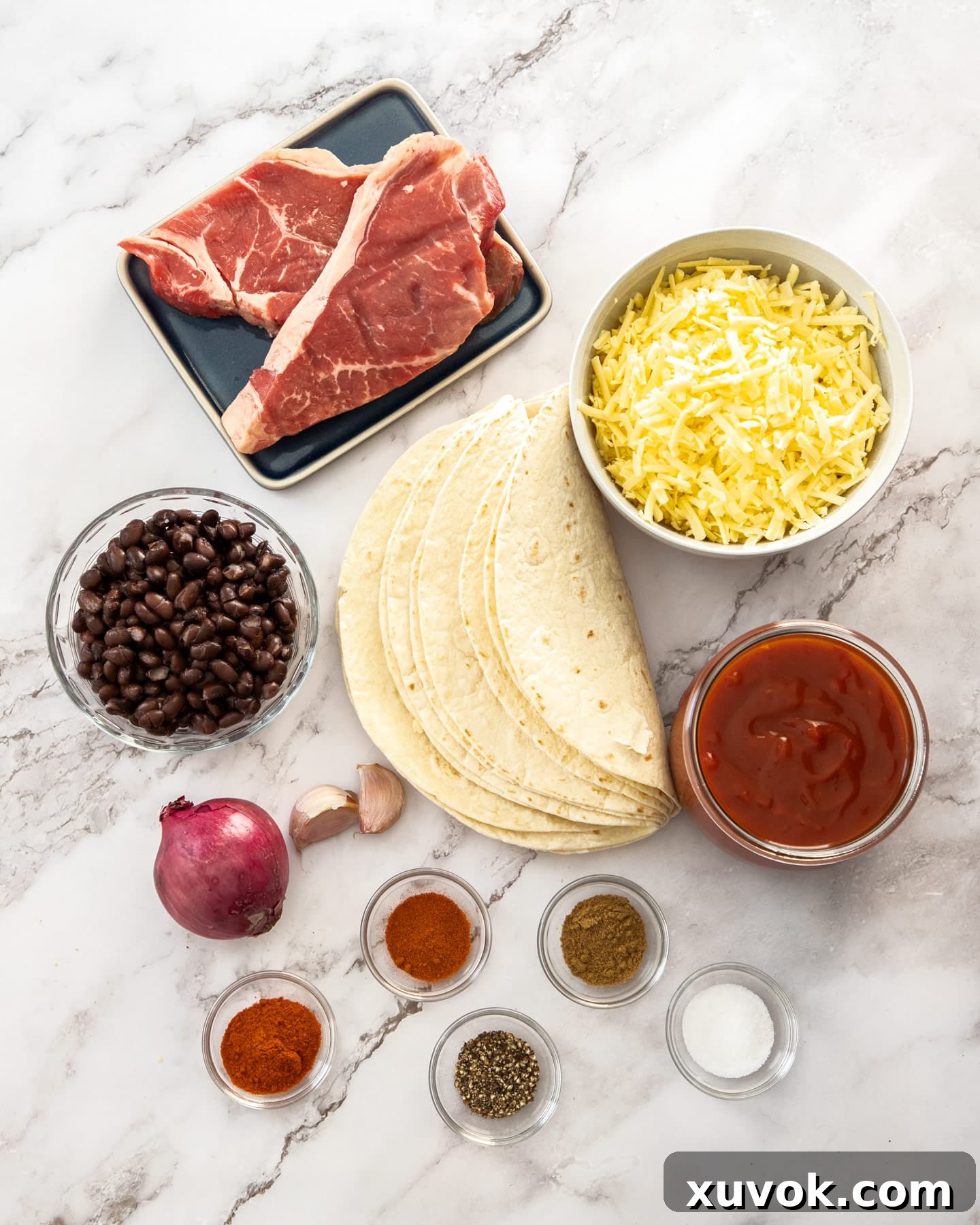 Ingredients for steak enchiladas on a marble surface.