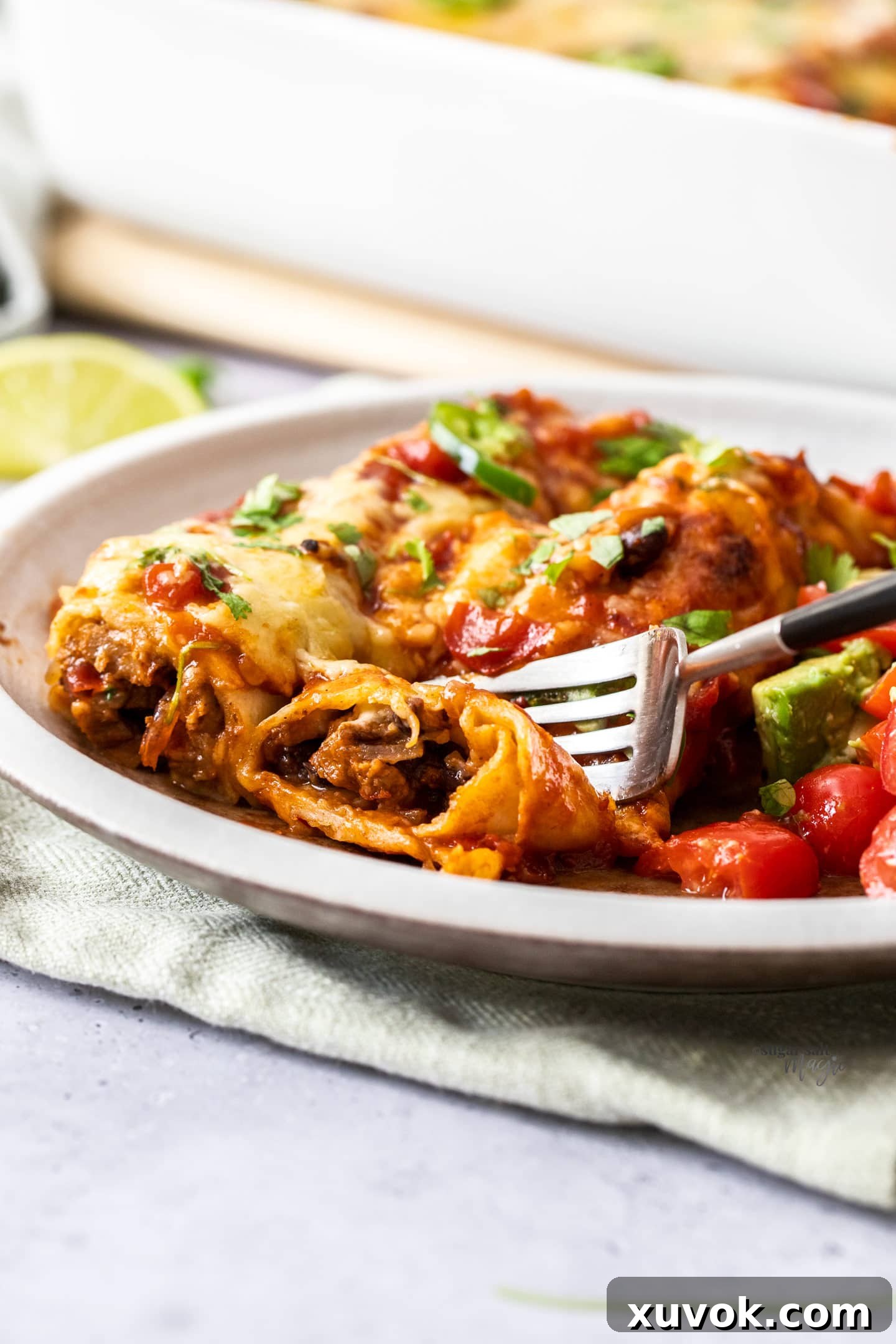 A fork cutting into steak enchiladas on a plate.