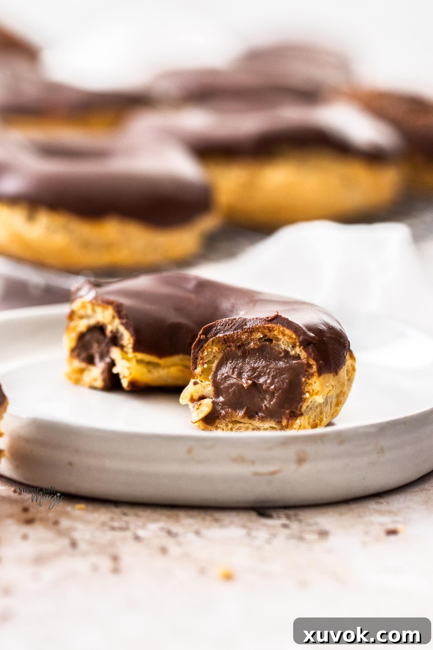 A chocolate chouxnut sliced open, revealing its rich, creamy chocolate pastry cream filling.