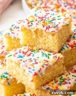 A stack of squares of sponge tray bake topped with sprinkles.