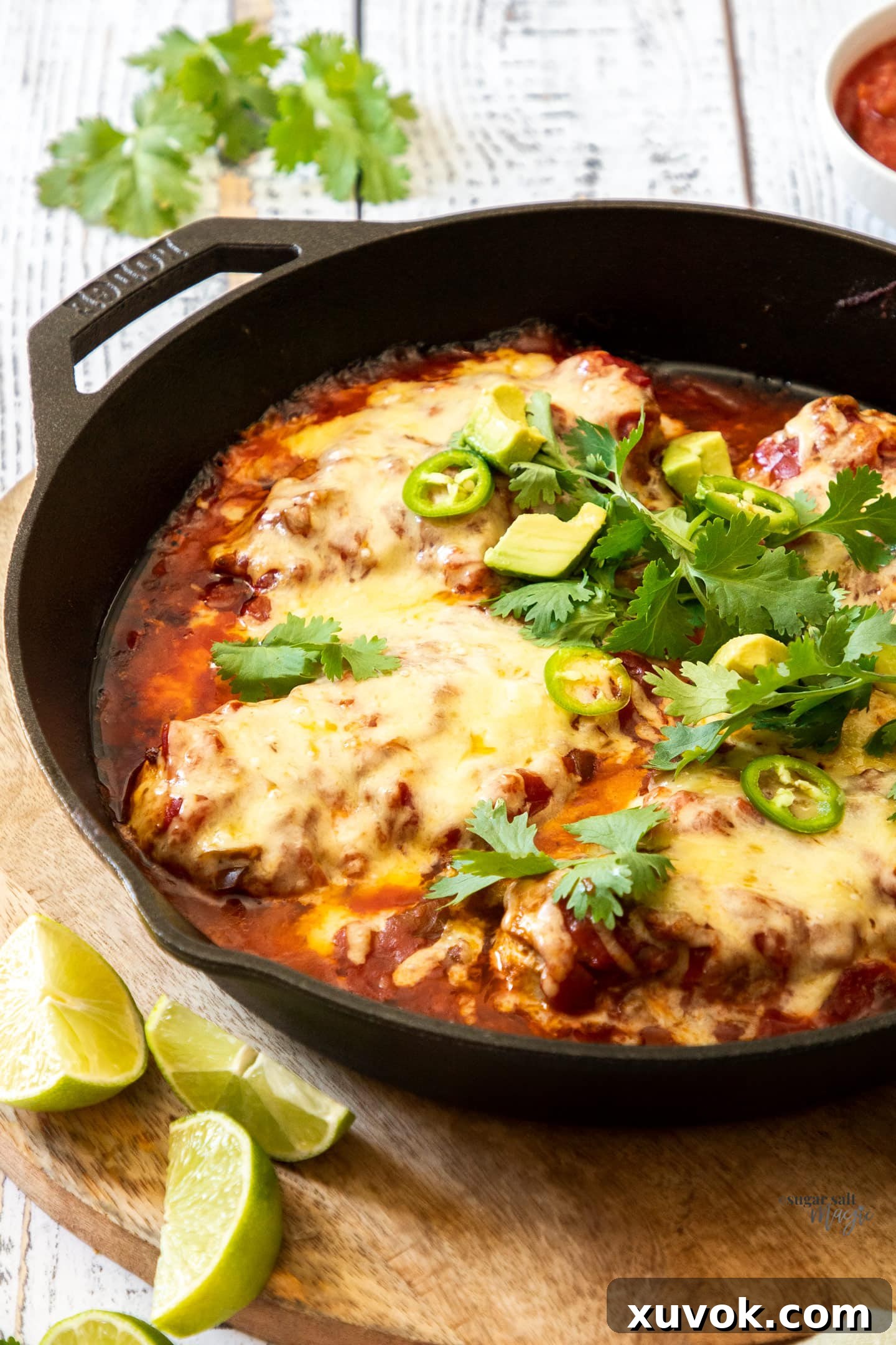 Closeup of golden-brown baked chicken salsa, bubbling with cheese in a cast iron skillet, garnished with fresh cilantro.