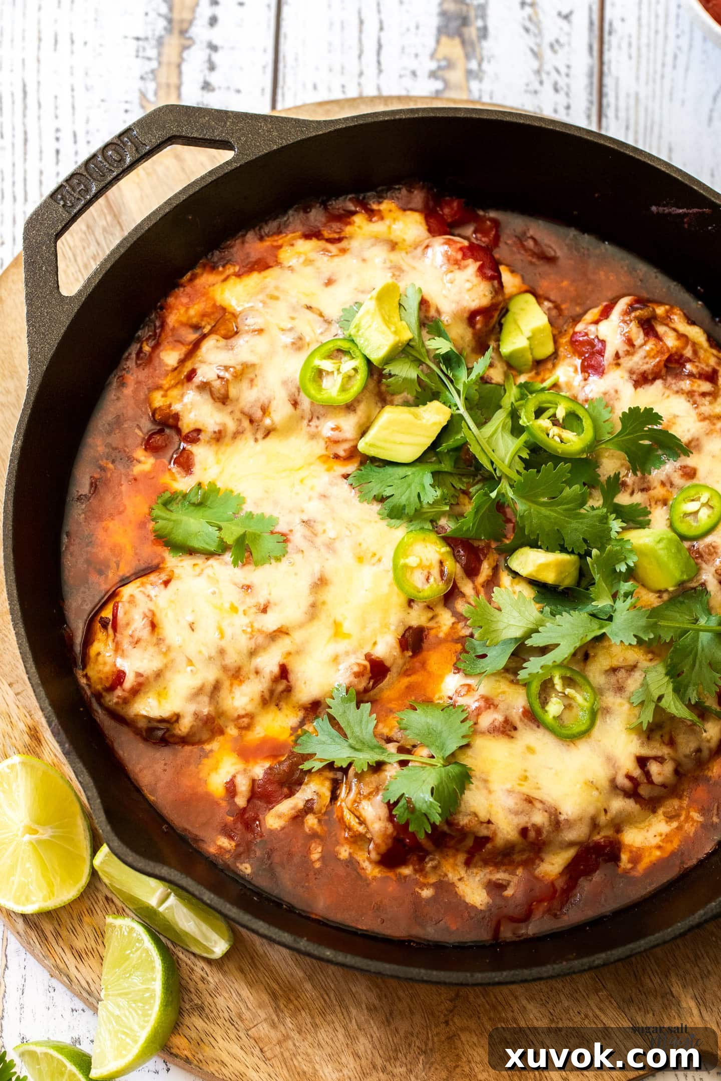 Top-down view of a cast iron skillet overflowing with cheesy, baked chicken in salsa, ready to be served.