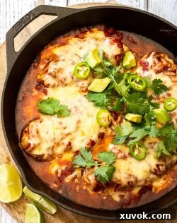 Top down view of baked chicken salsa in a cast iron skillet topped with cilantro and jalapenos.