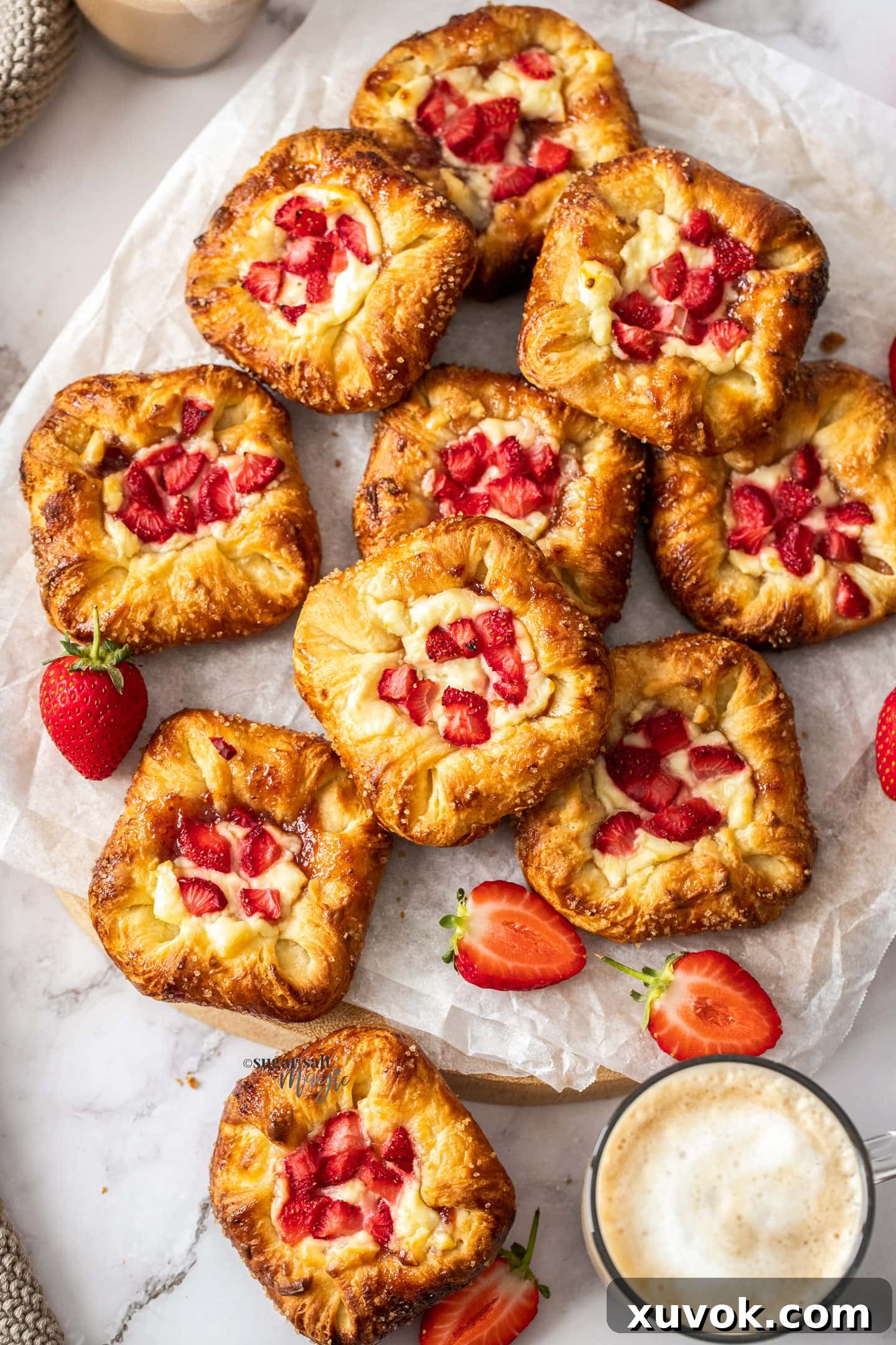 Top down view of 10 strawberry Danishes on a timber board, beautifully arranged.