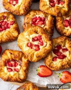 Top down view of a batch of strawberry danishes on a timber board.