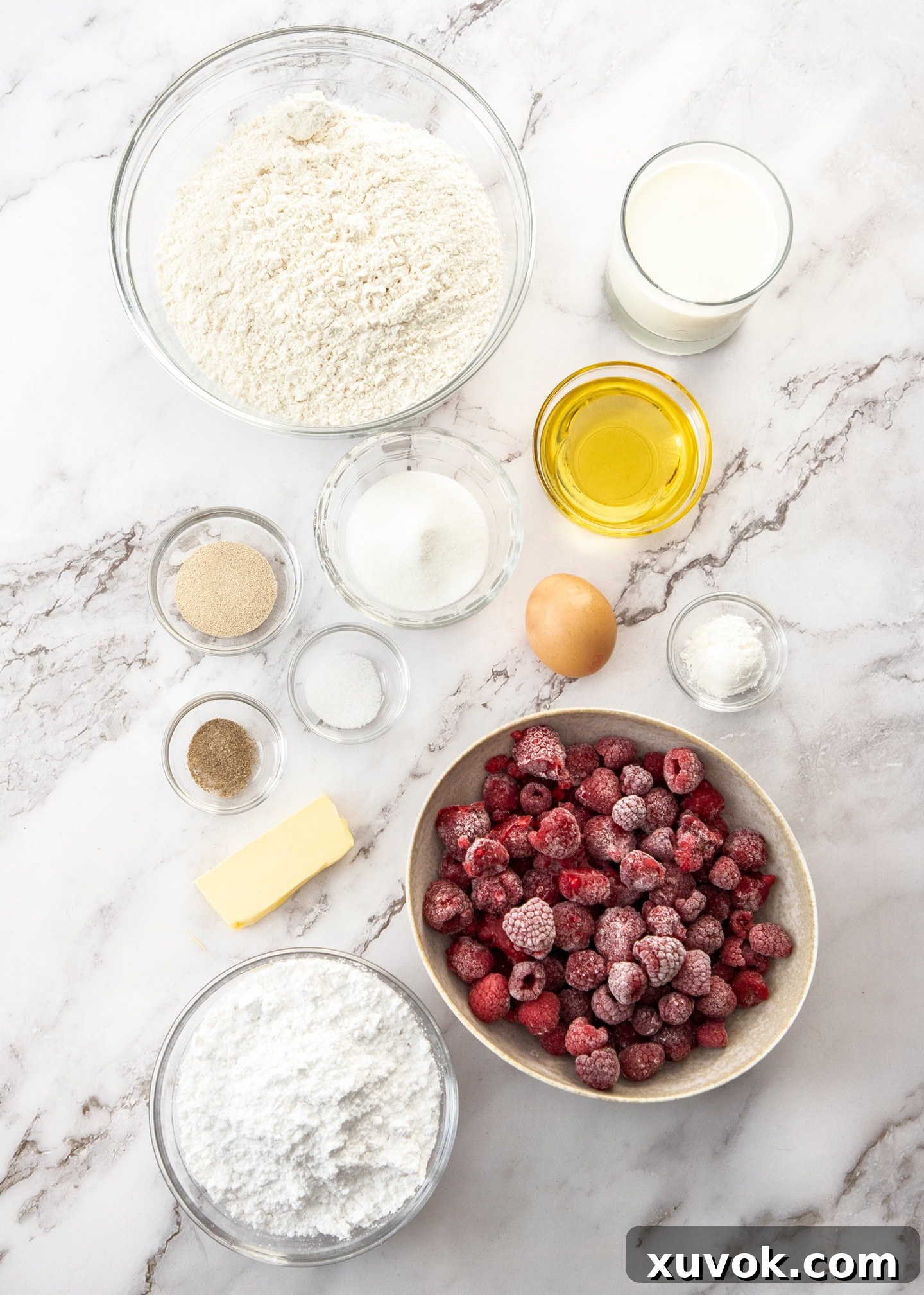 Ingredients for raspberry sweet rolls on a marble surface.