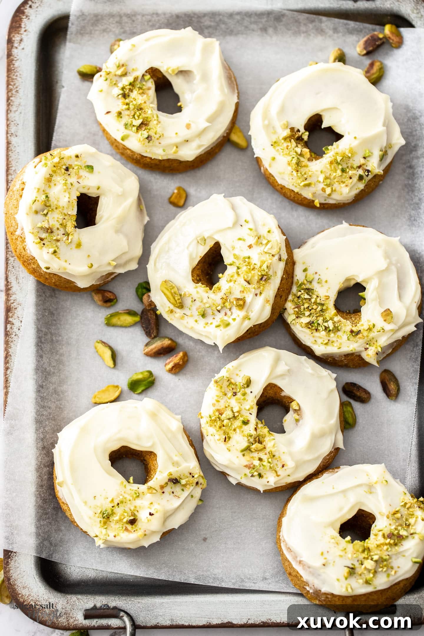 Top down view of 8 carrot cake donuts on a metal serving tray.