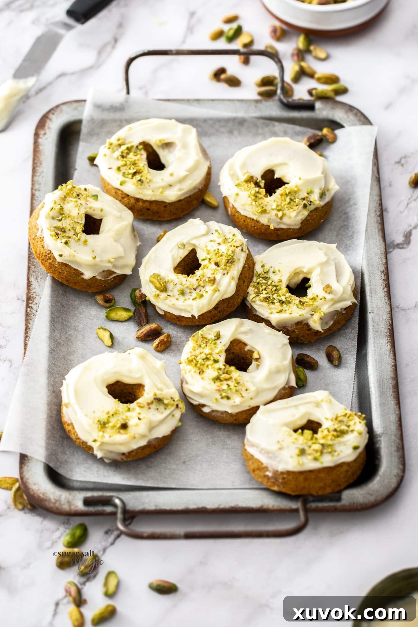 A batch of 8 carrot cake donuts on a metal serving tray.