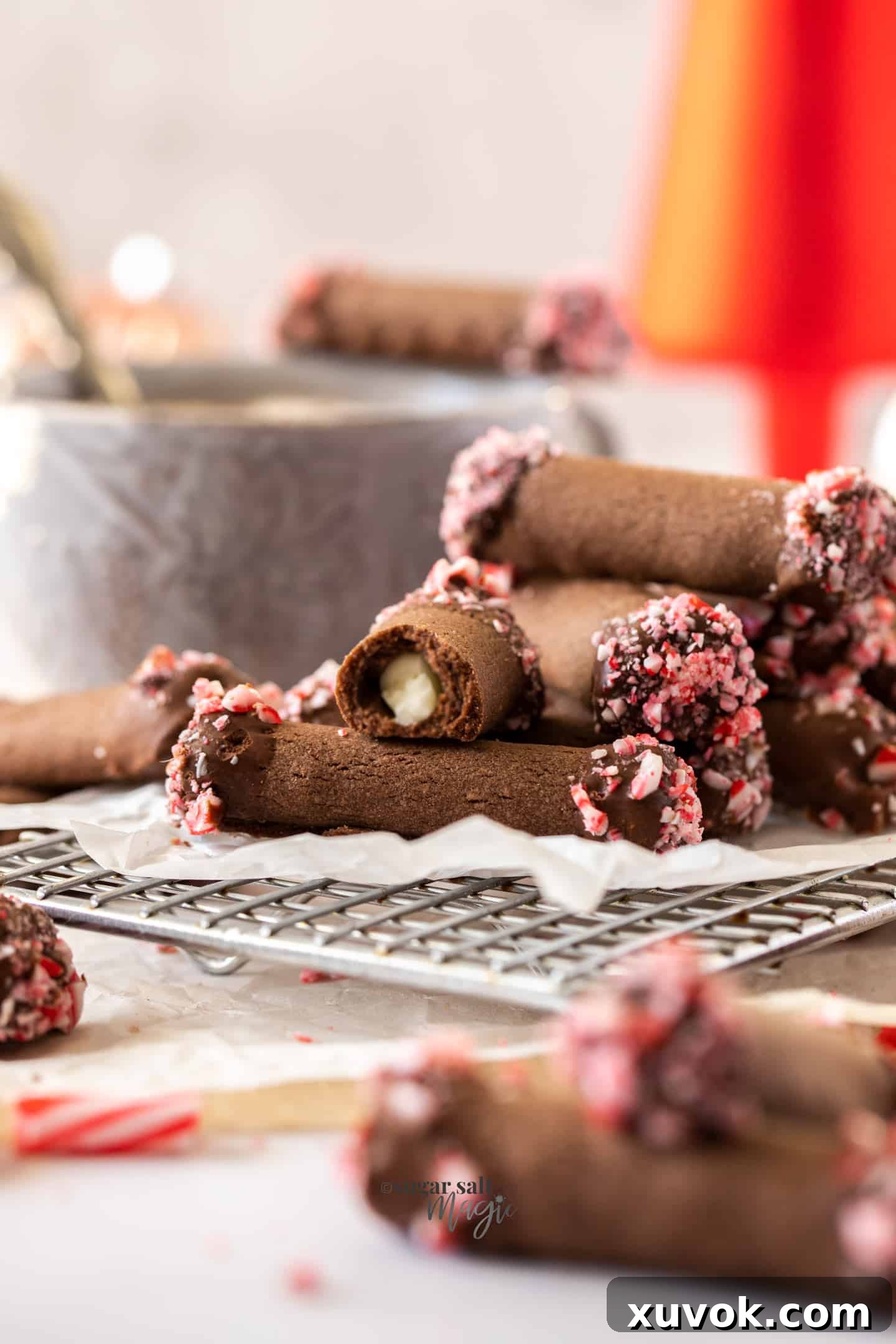 A stack of beautifully crafted chocolate roll cookies, with one expertly broken in half to reveal the vibrant peppermint filling.