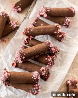 A row of chocolate roll cookies on a sheet of baking paper, ready for their final decorative touches.