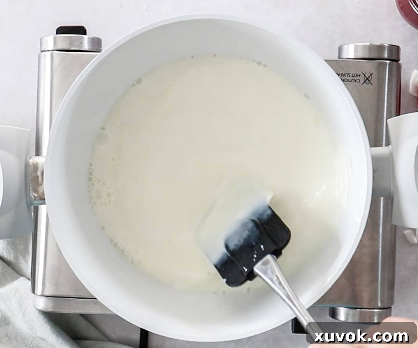 Stirring the gelatine and sugar into the milk in a pan.