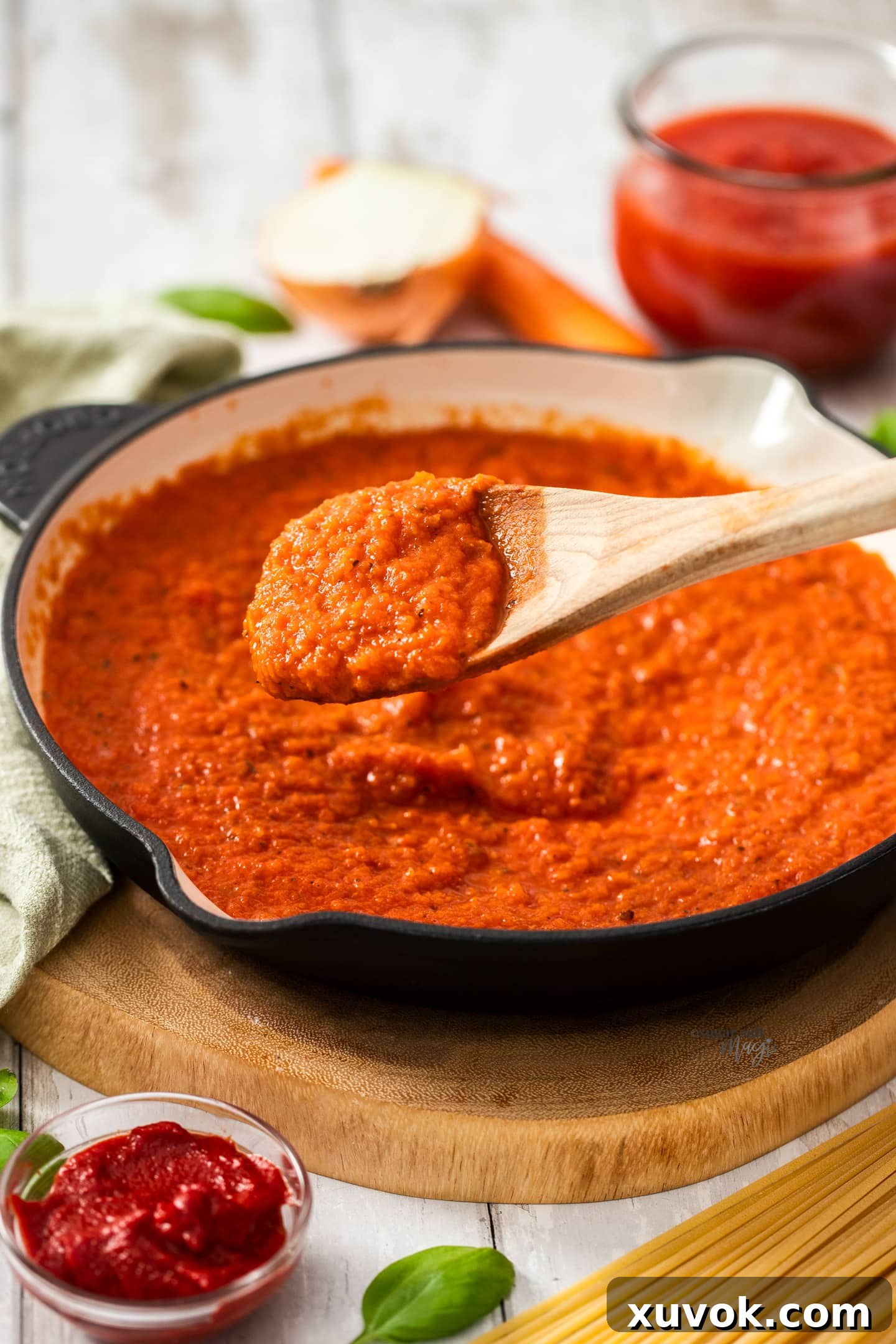 A vibrant red Napoletana sauce simmering gently in a stainless steel skillet. The texture is smooth with visible specks of herbs, indicating a fresh, homemade quality, ready to be tossed with pasta. Steam rises delicately, highlighting its warmth and inviting aroma.