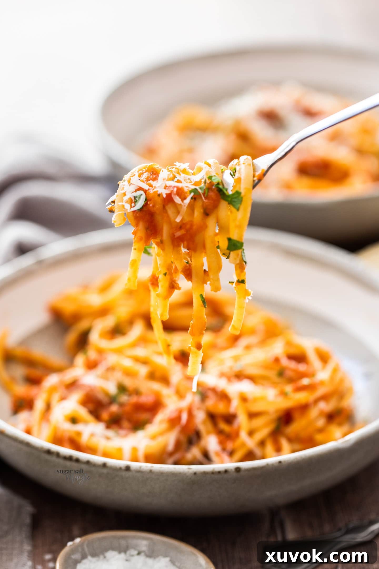 A close-up, beautifully composed shot of perfectly cooked spaghetti, elegantly twirled around a silver fork. The pasta demonstrates an ideal al dente texture, inviting immediate enjoyment, set against a softly blurred background.
