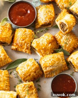 Close up of golden turkey sausage rolls on a baking tray with herbs, ready to be served.