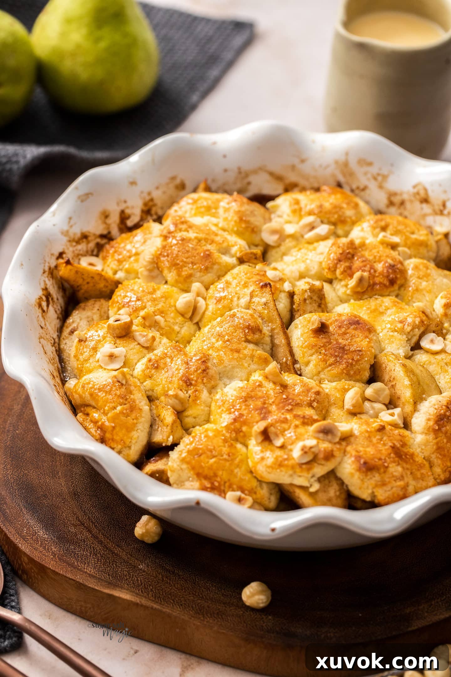 A white pie dish filled with baked pear cobbler, golden brown topping visible.