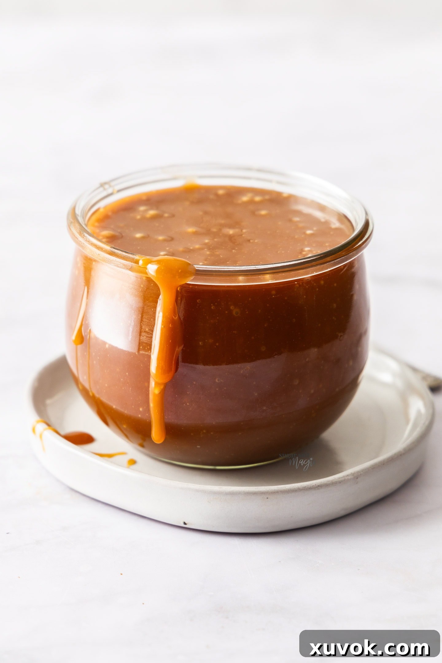 The homemade caramel sauce stored beautifully in a glass jar, with a delicious drip down the side.
