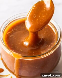 Closeup of a spoon taking caramel out of the jar.