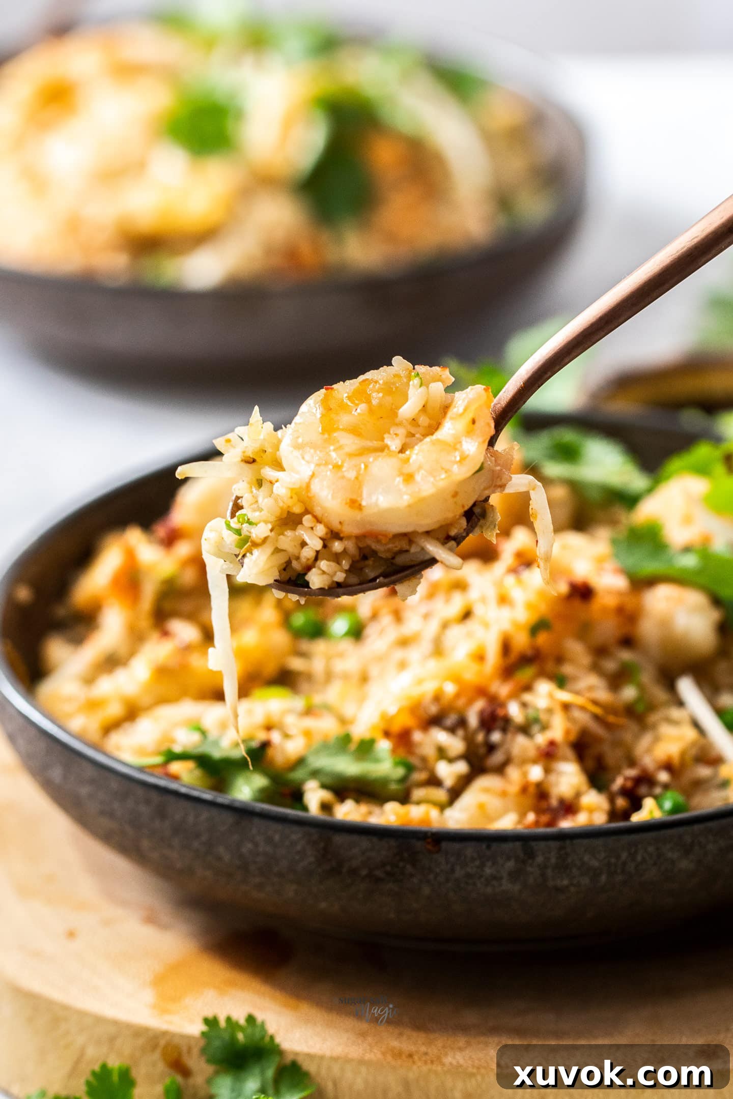 A spoonful of prawn fried rice, showcasing the fluffy rice grains, peas, egg, and plump prawns.