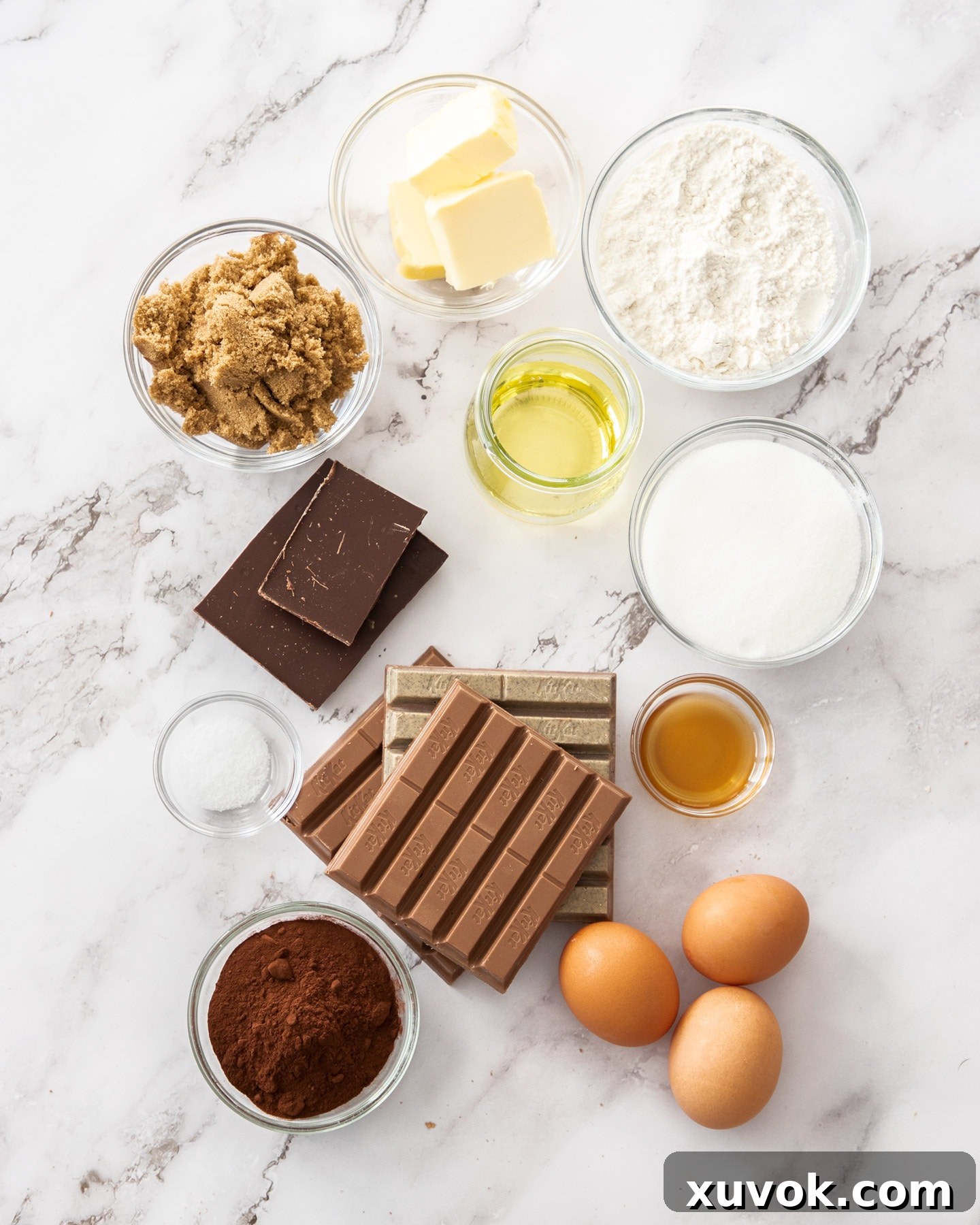 A curated display of all the ingredients for Kit Kat brownies neatly arranged on a sleek marble surface.
