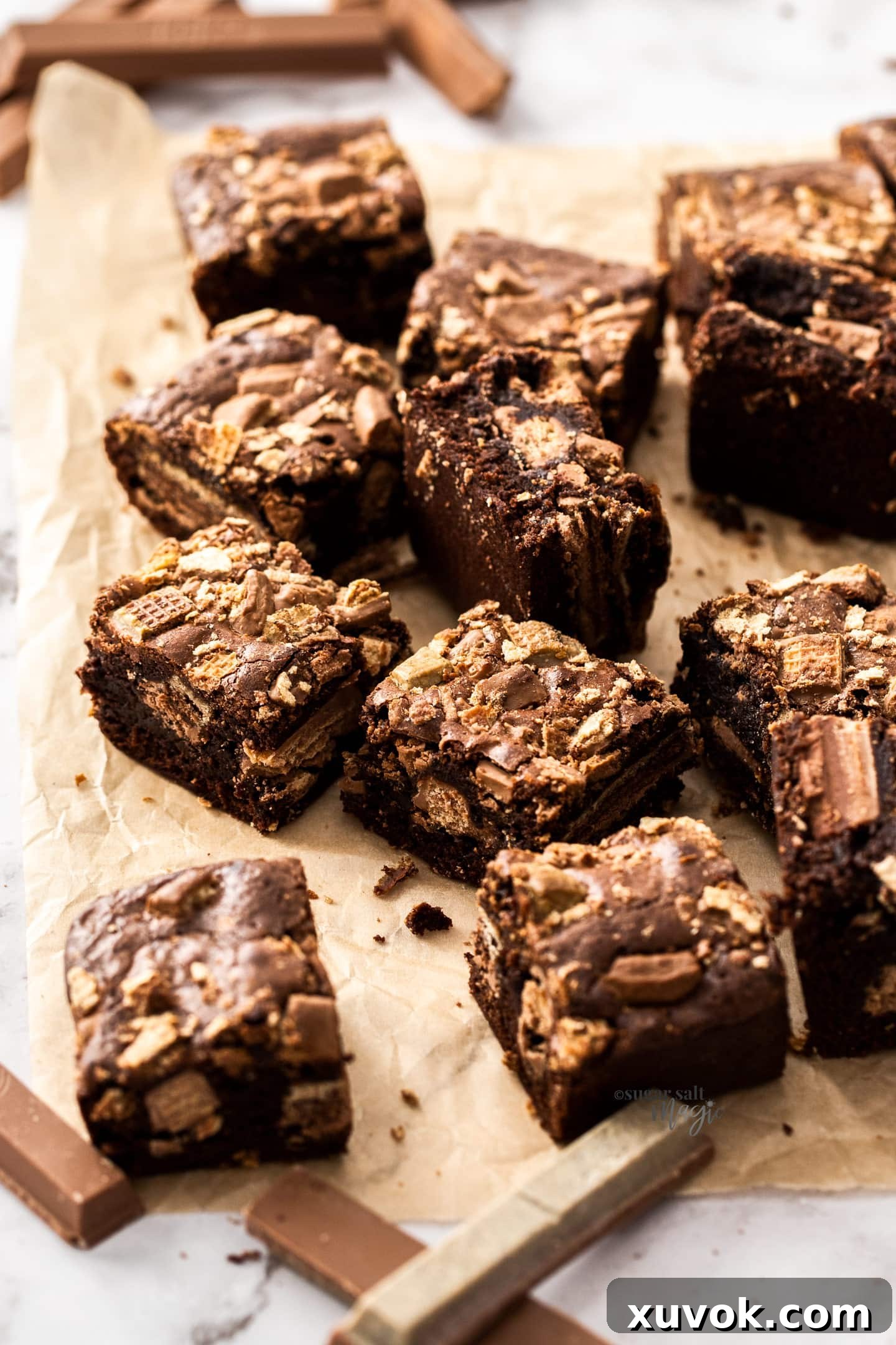 A pristine batch of freshly baked Kit Kat brownies laid out on a sheet of parchment paper, showcasing their even cuts and delicious appearance.
