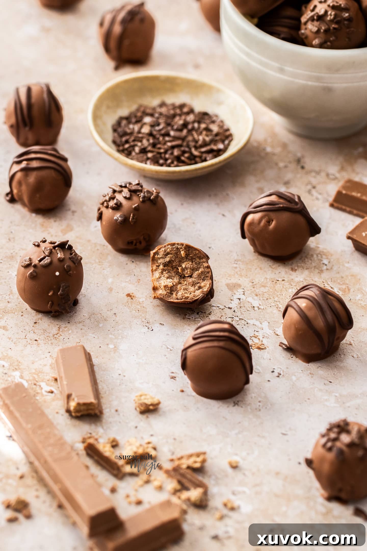 A batch of kitkat truffles on a stone surface with one broken in half.