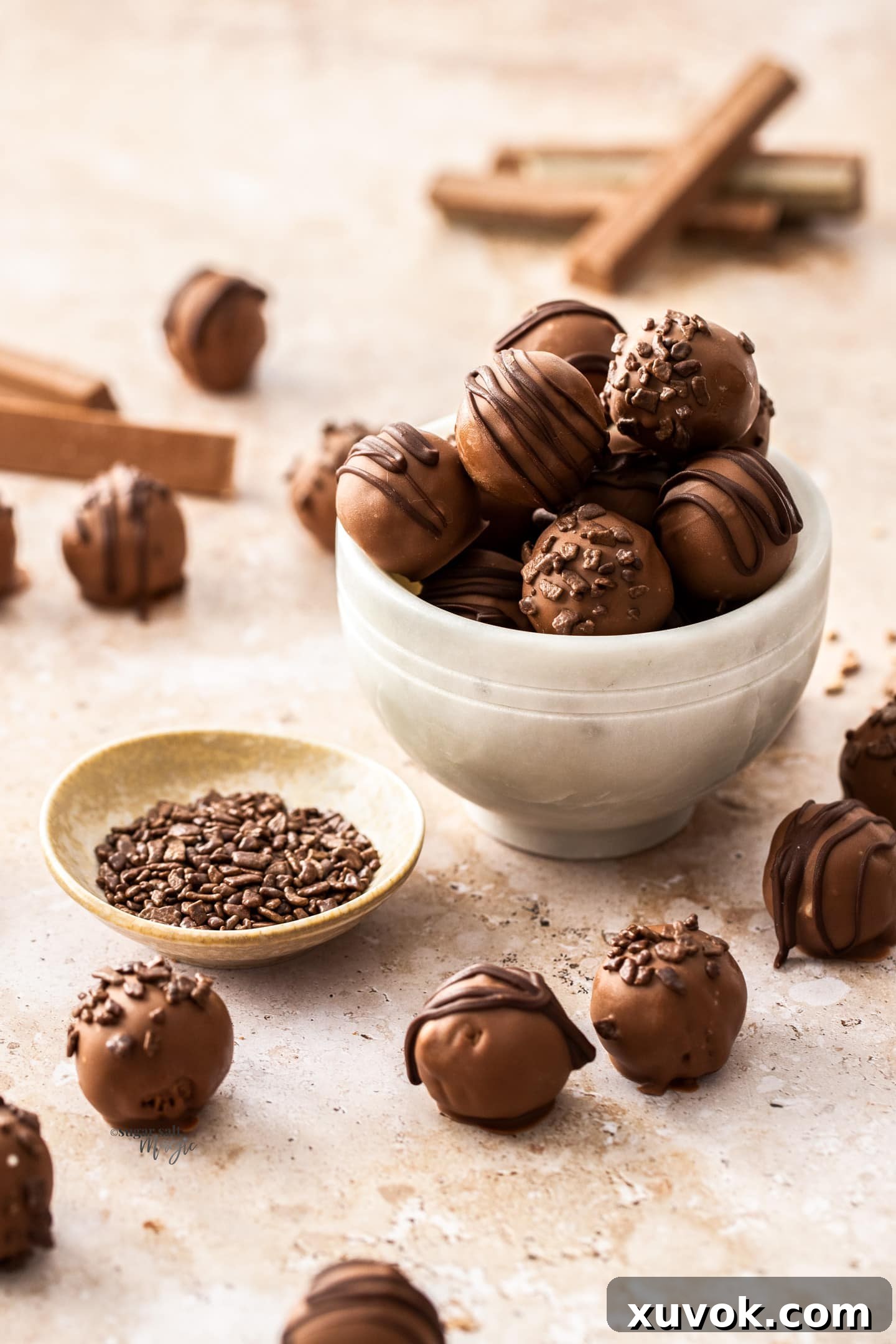A marble bowl filled with kit kat truffles next to a pinch bowl of chocolate sprinkles.