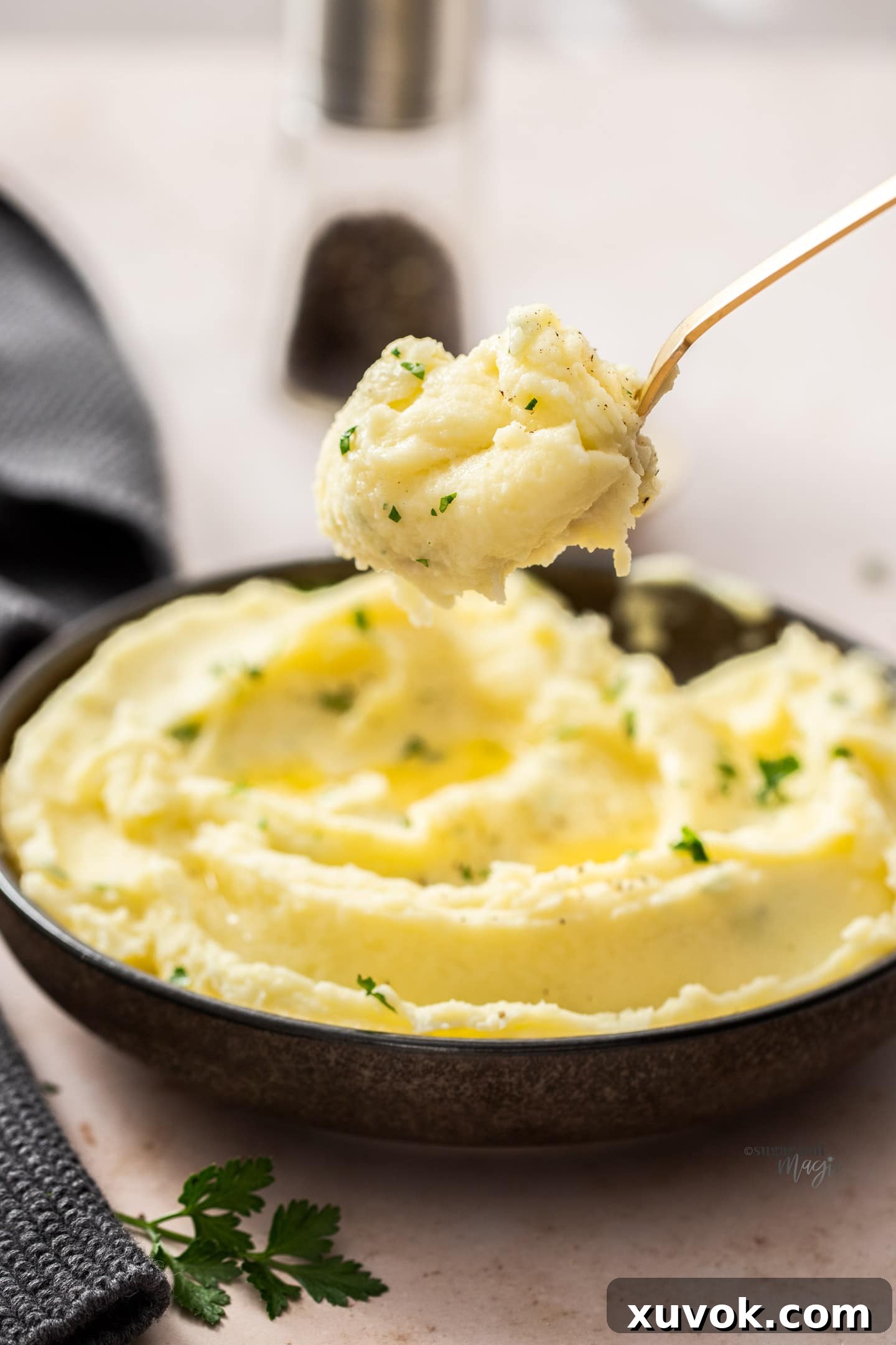A spoonful of mashed potato being taken from a bowl.