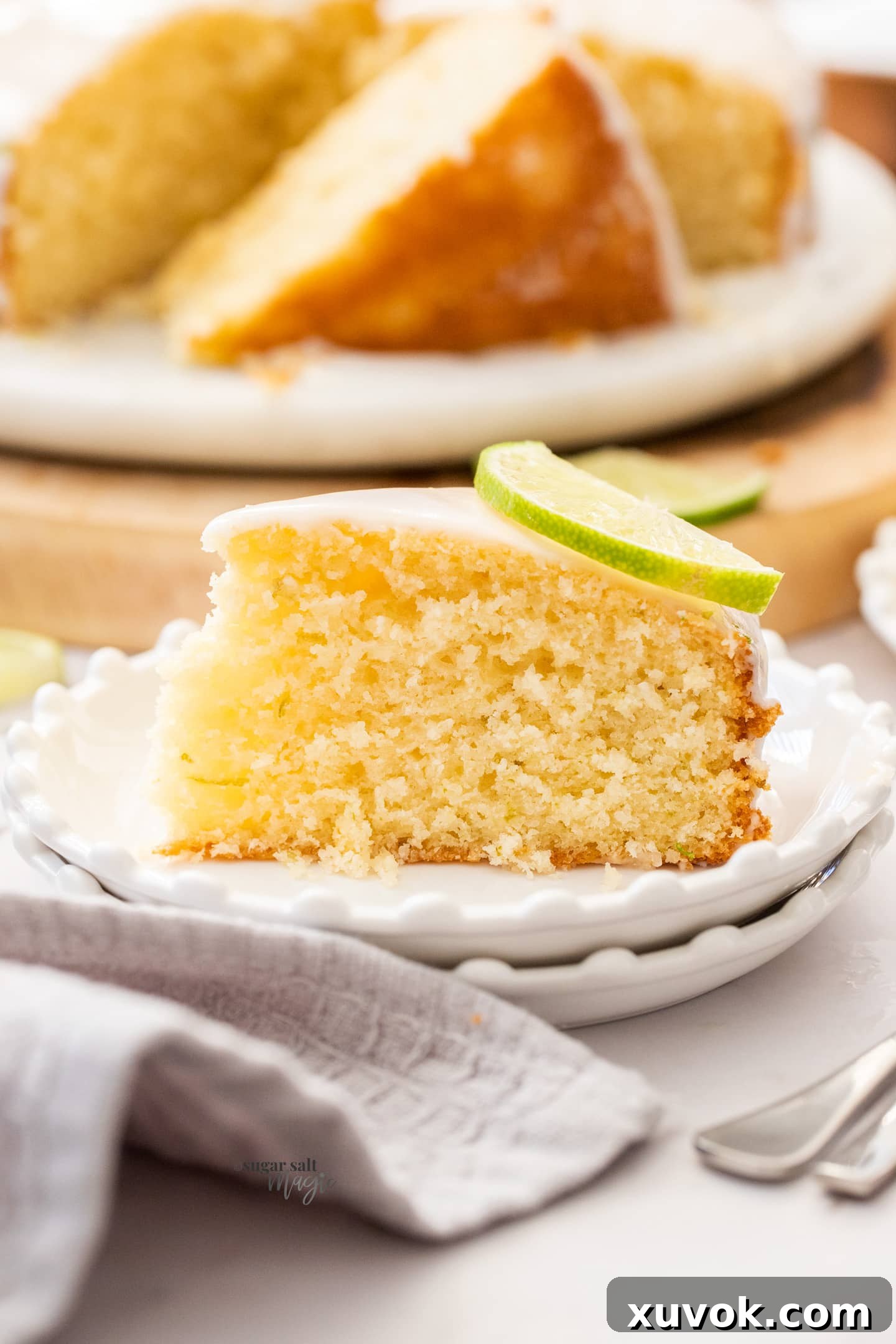 A beautifully sliced piece of lime and coconut cake on a small dessert plate, showcasing its moist texture and vibrant lime glaze.