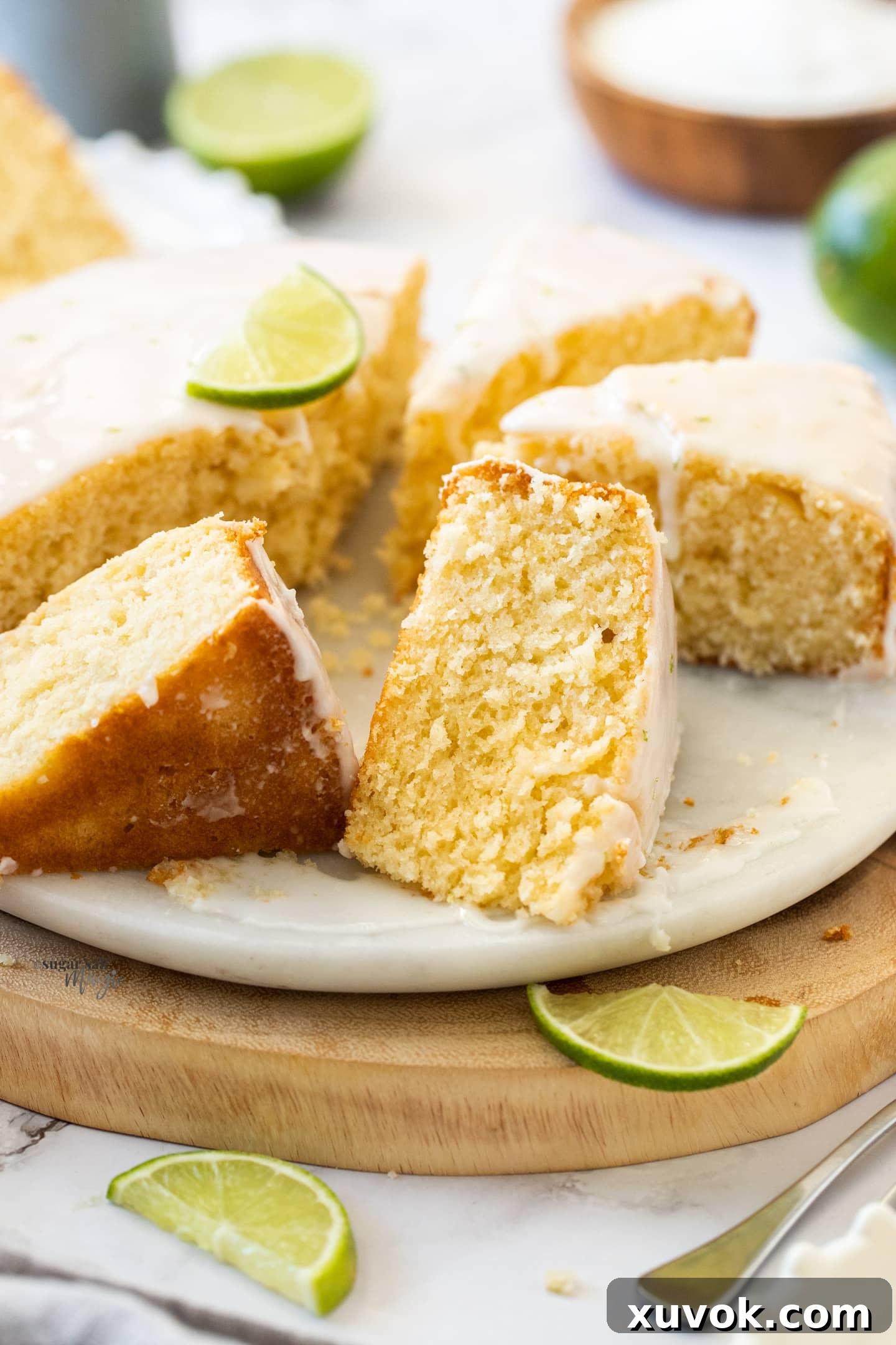 A close-up shot of a single slice of lime and coconut cake, showing the texture of the cake and the glaze.