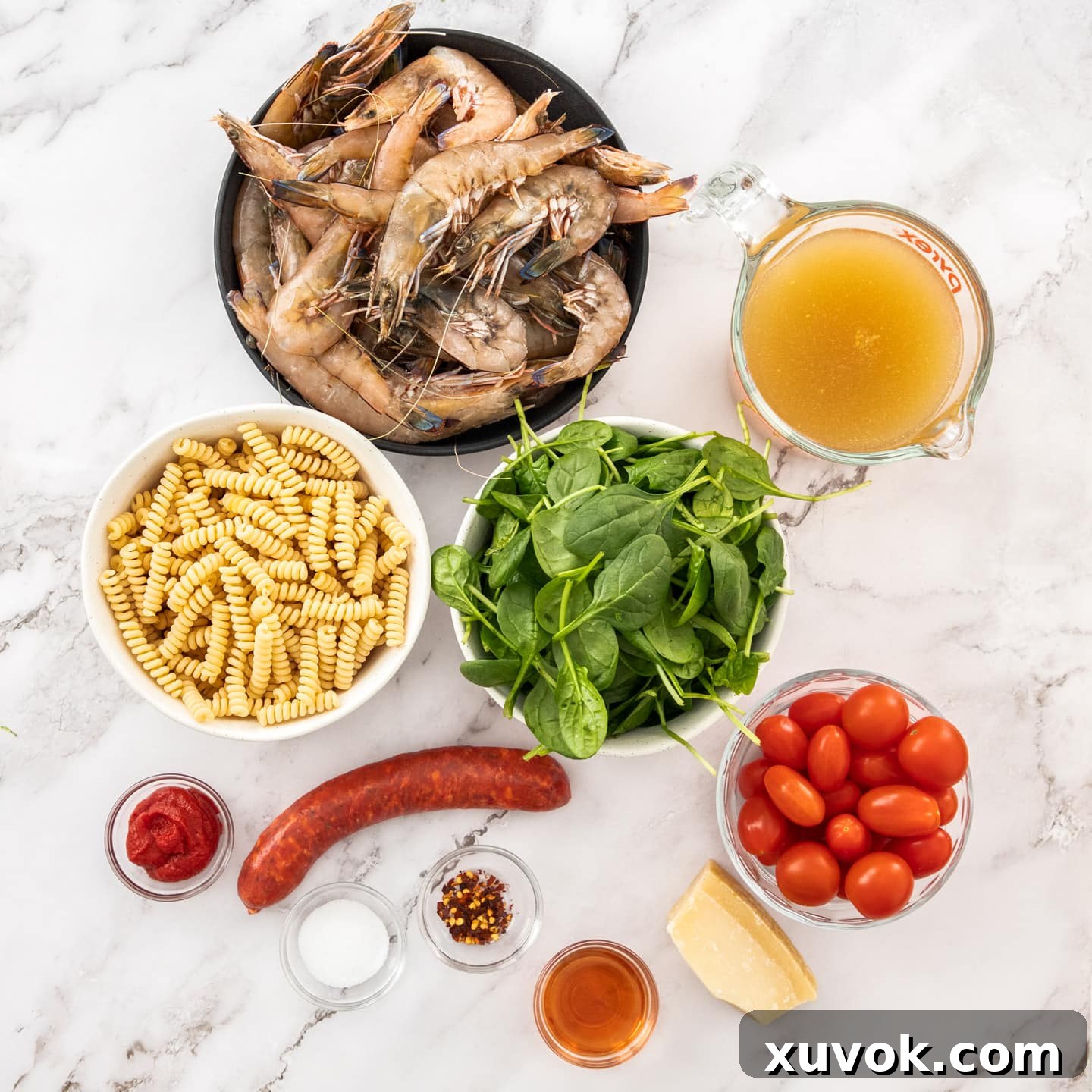 Fresh ingredients for prawn and chorizo pasta on a sleek marble surface, ready for cooking.