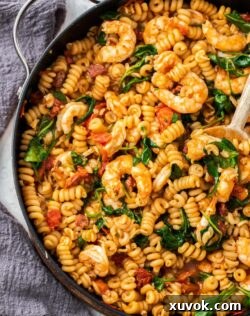 Top down view of prawns in pasta in a large skillet, ready to serve.