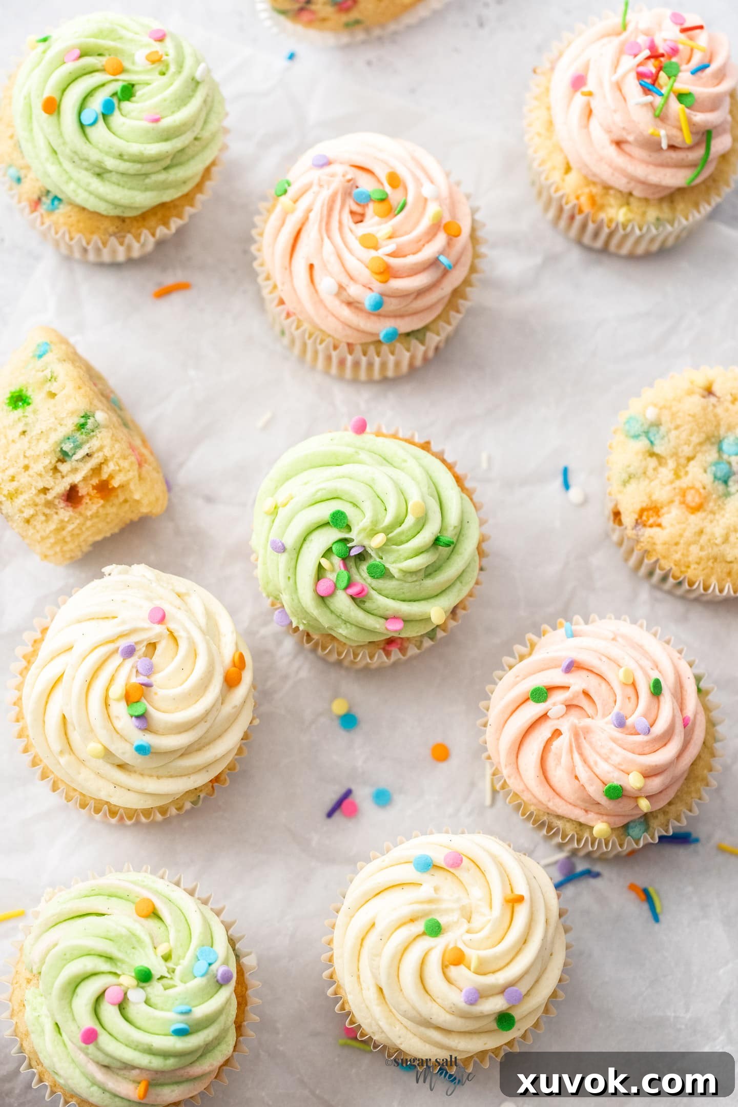 Top down view of a batch of confetti cupcakes decorated with colorful sprinkles and creamy frosting.