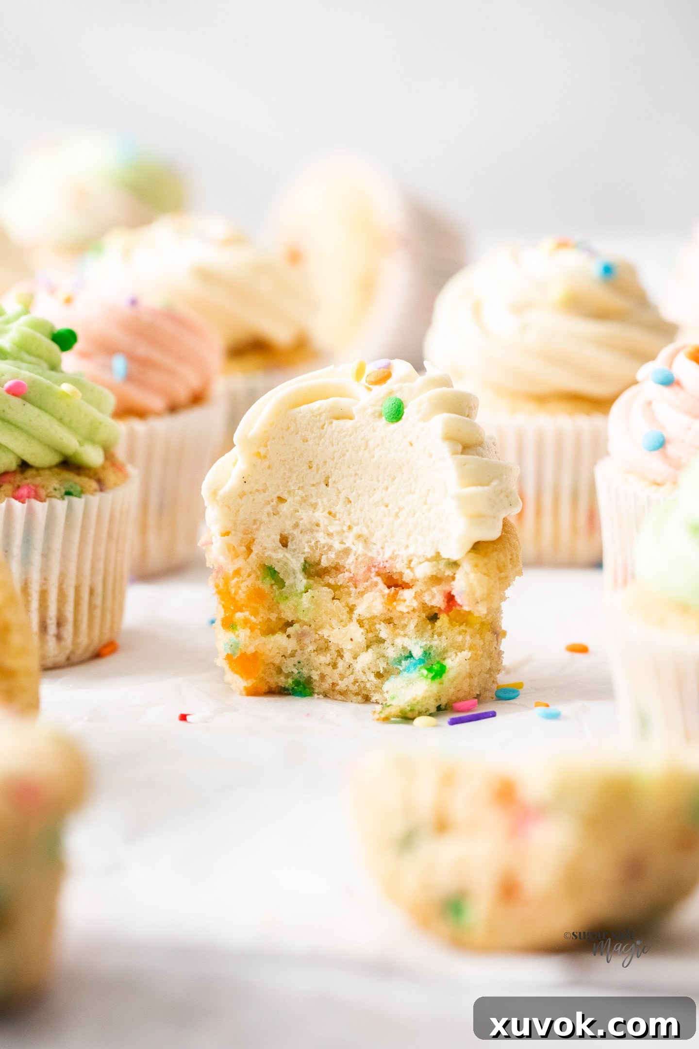 Closeup shot of the inside of a confetti cupcake, revealing its moist, sprinkle-filled crumb and creamy frosting.