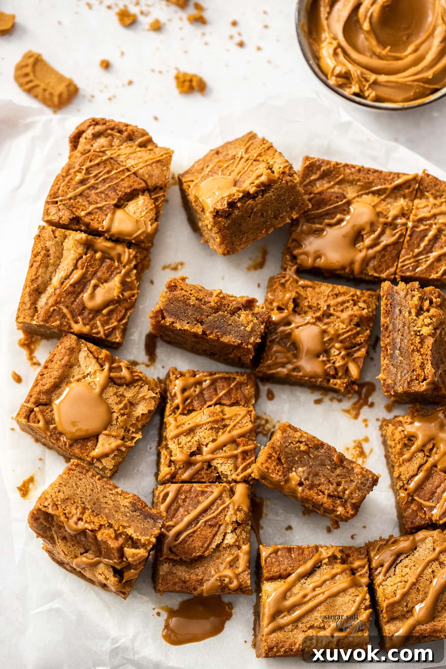 A close-up shot of a batch of freshly baked Biscoff blondies, with one square cut in half to clearly show its dense, fudgy interior texture studded with cookie pieces.