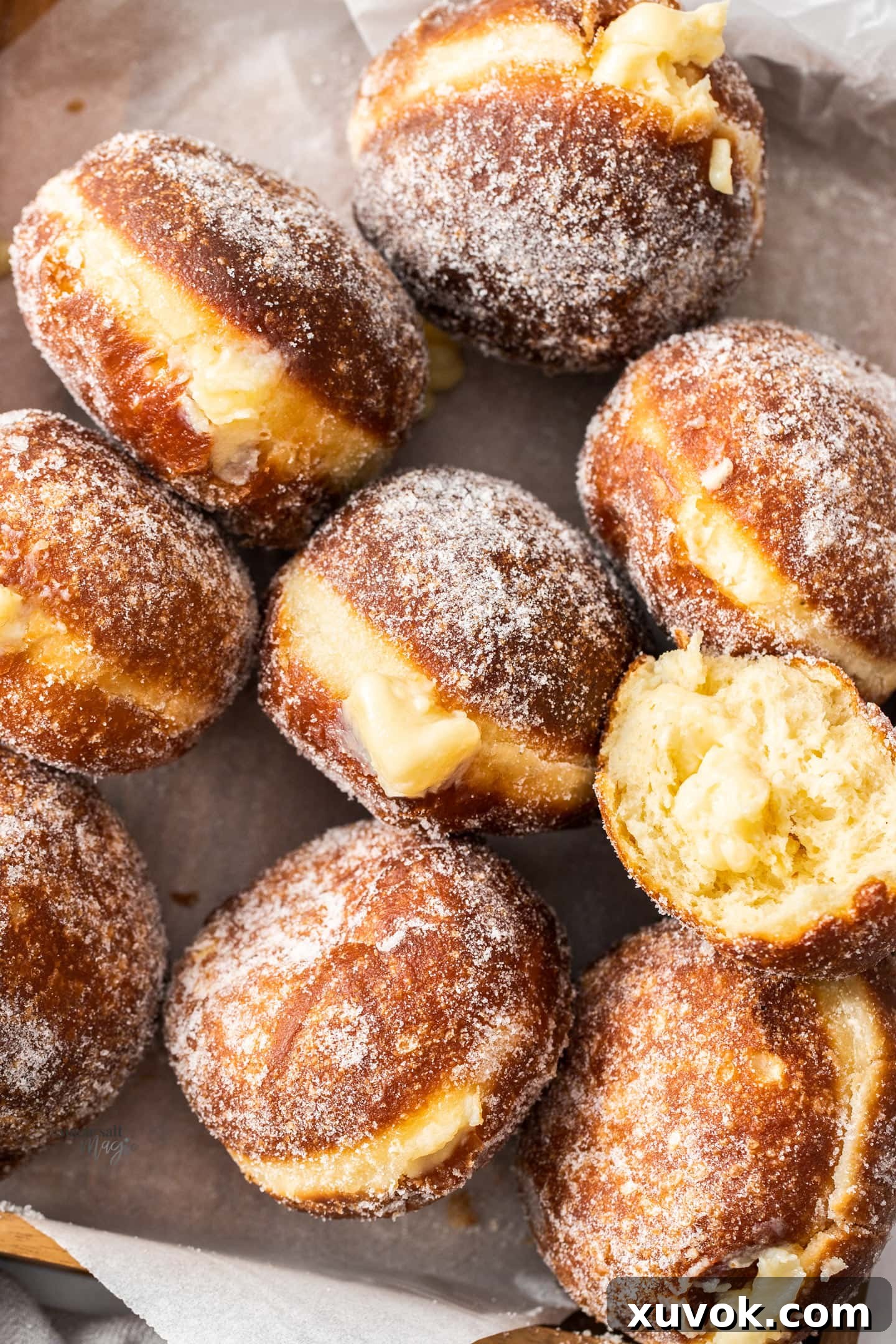 A wooden tray filled with golden-brown Bavarian cream donuts, showcasing their fluffy texture and delicious appearance. Each donut is generously coated in sugar and ready to be filled.
