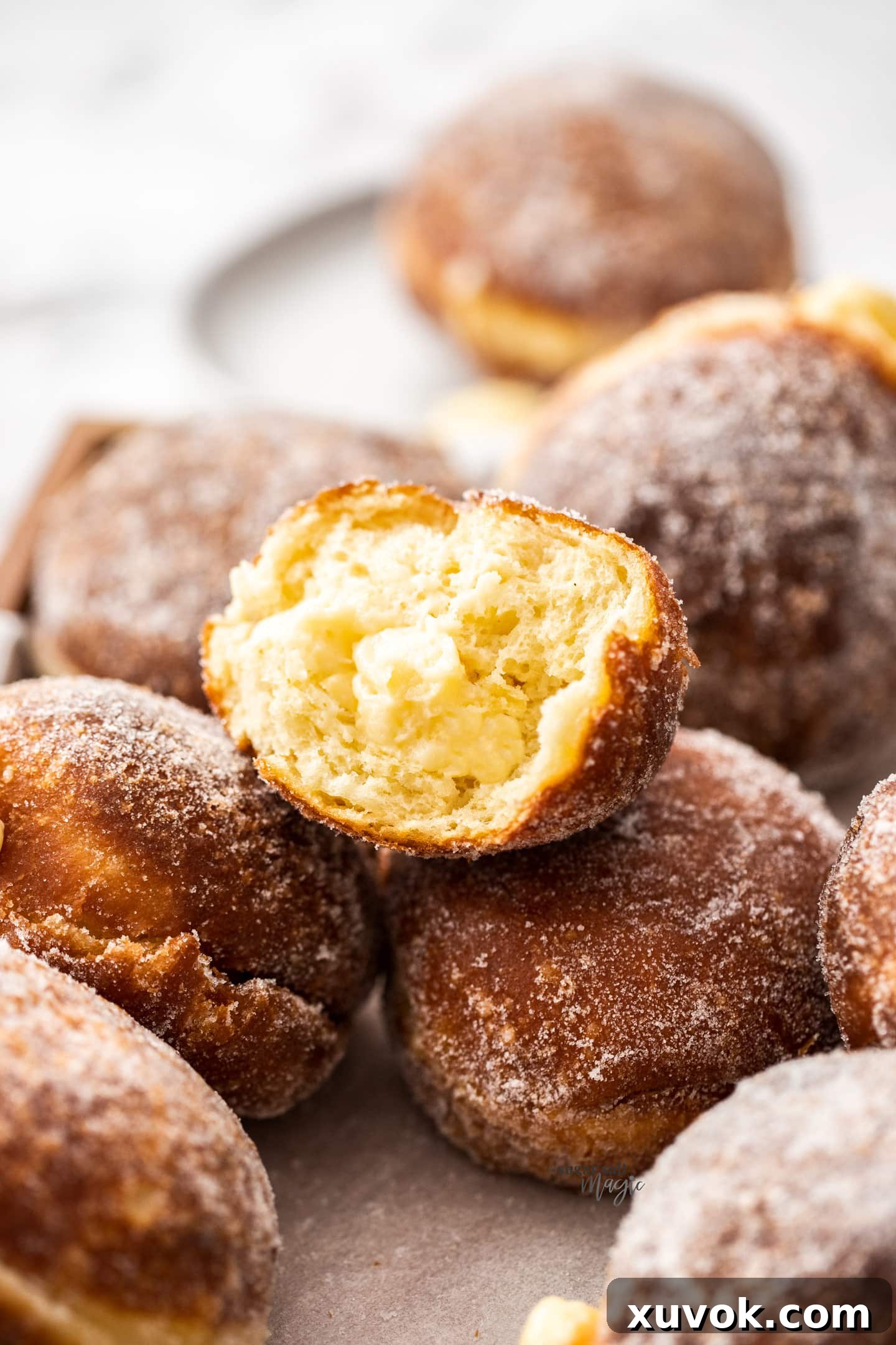 The cross-section of a perfectly filled Bavarian cream donut, revealing its airy interior and generous amount of luscious vanilla pastry cream.
